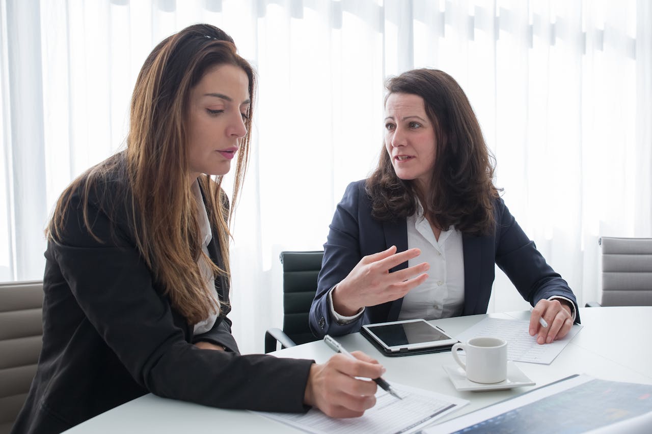 Women in Black Blazer Sitting Near the Table while Having Conversation